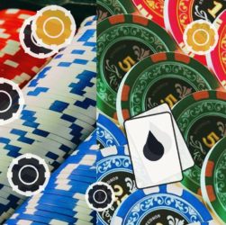 Pile of red, blue, and green casino chips with white target marks and a playing card featuring a black droplet symbol on top