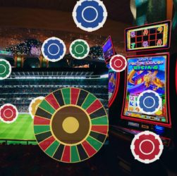 Casino interior with a large roulette wheel, slot machines, and a bright stadium-style screen in the background.