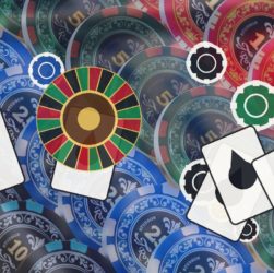 Assorted casino chips, playing cards with red and black drops, and a roulette wheel on a colorful table surface.
